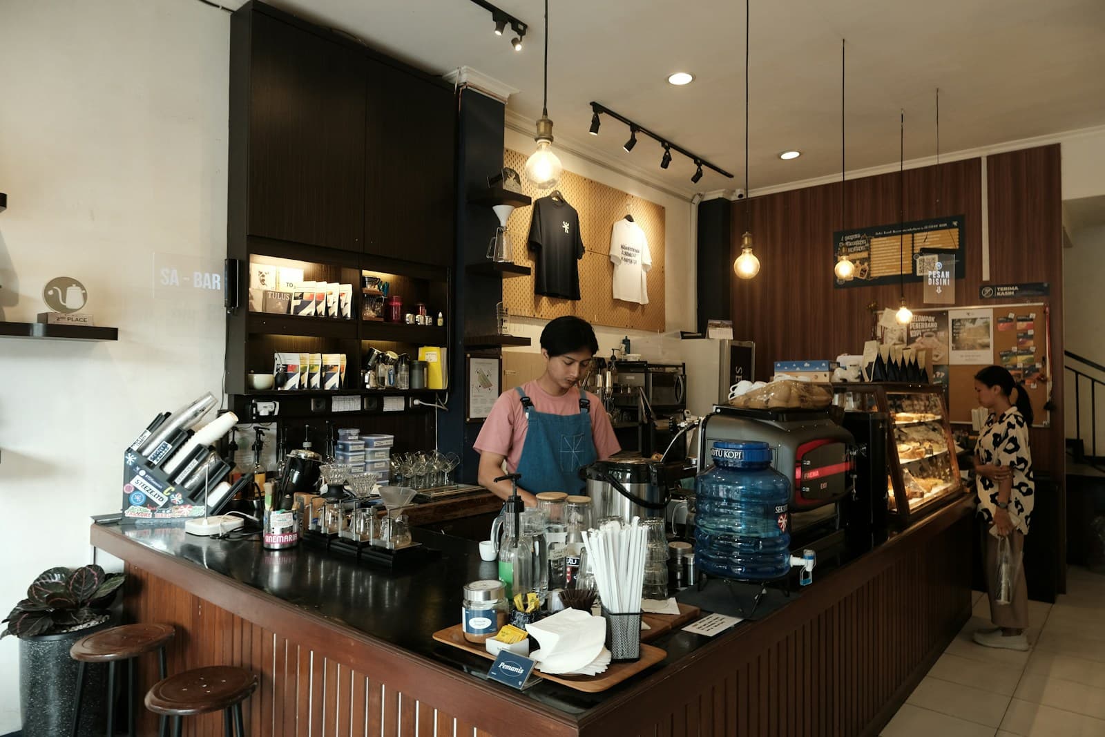 A barista behind the counter of a small coffee shop